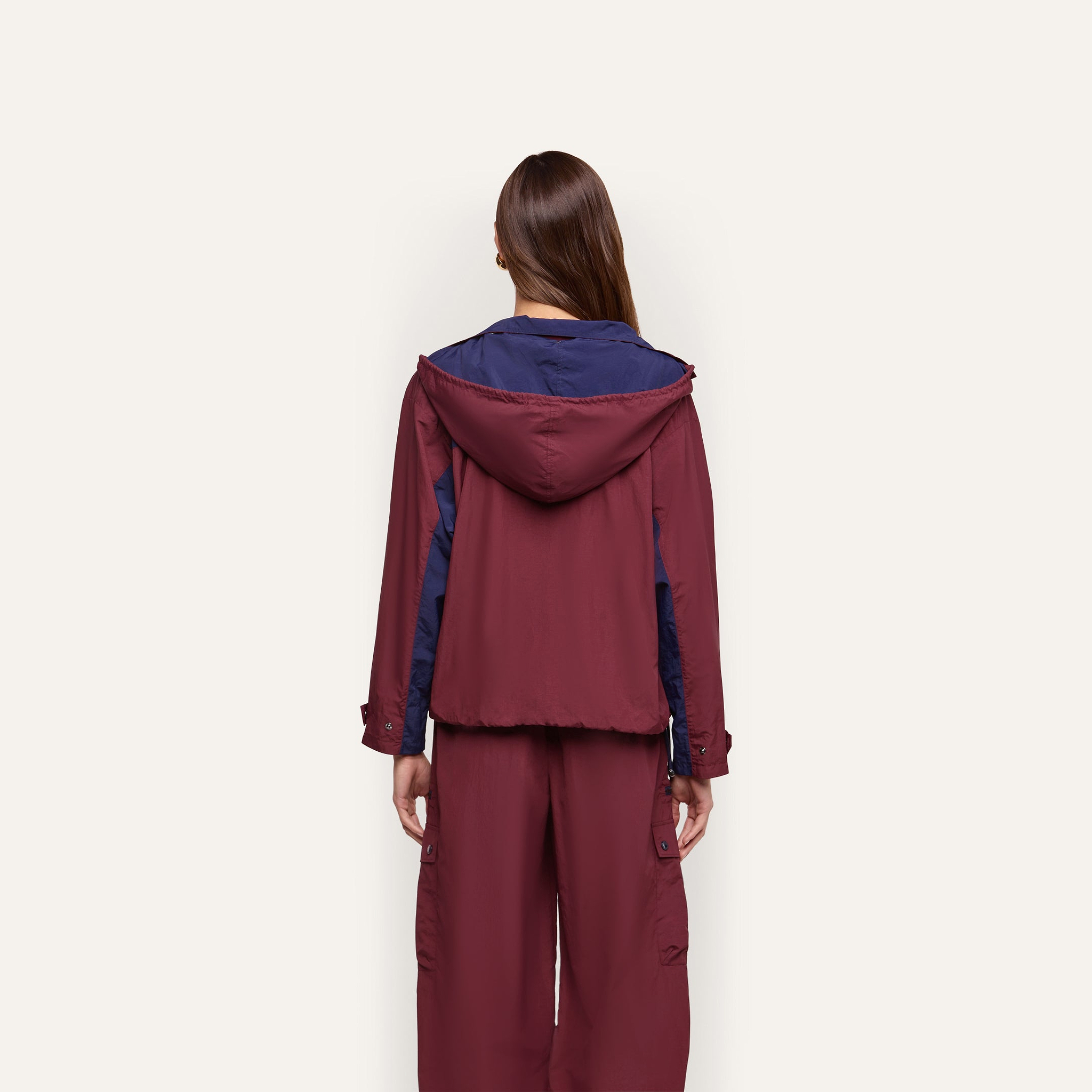 A person seen from behind wears a maroon and dark blue Geovana windbreaker with matching water-repellant trousers.
