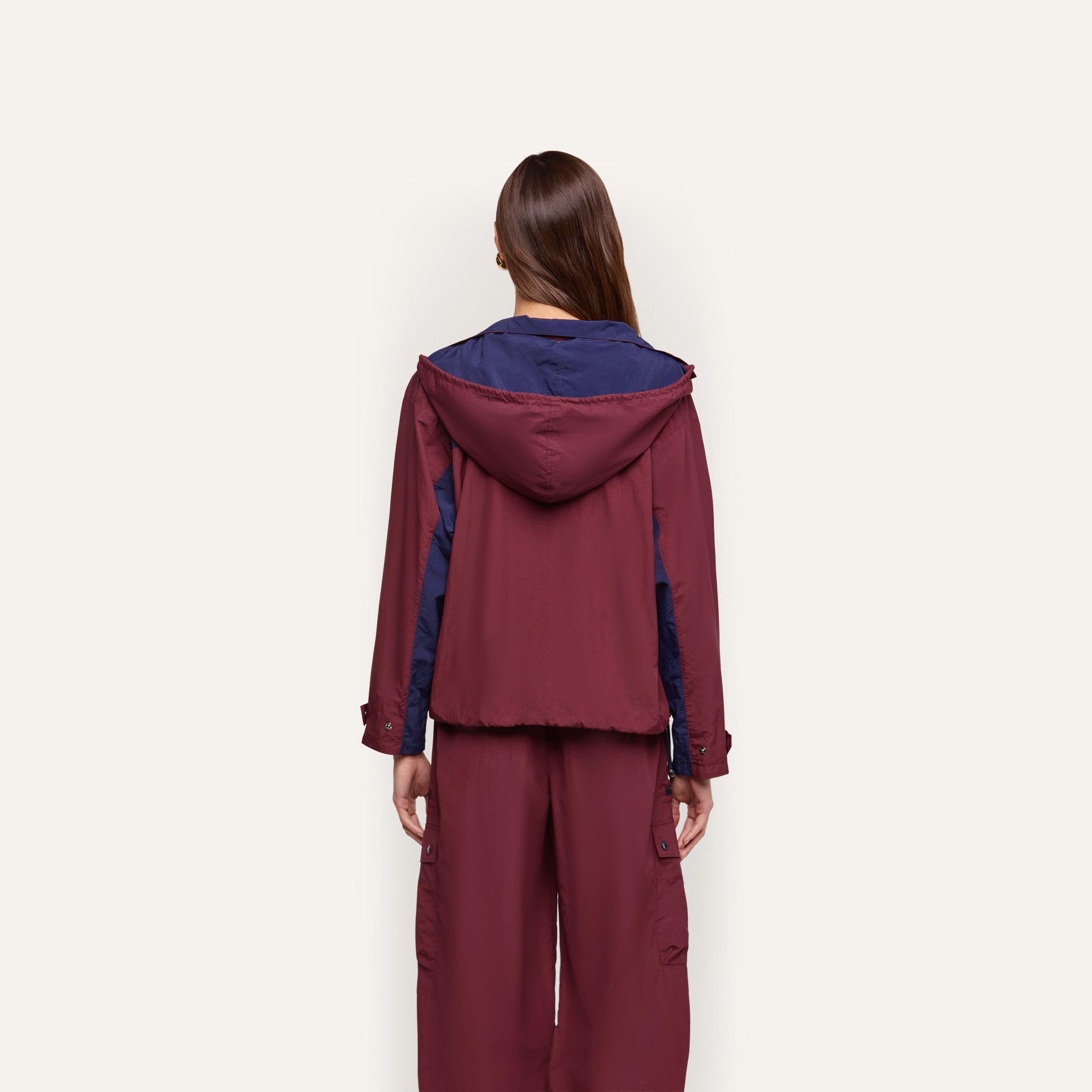 A person seen from behind wears a maroon and dark blue Geovana windbreaker with matching water-repellant trousers.