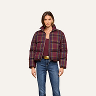 A woman wearing the Larsa Oversized Puffer Jacket over a maroon top, blue jeans, and a beige belt, standing against a plain light background.