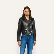A woman wears a Blakely Embroidered Leather Jacket featuring small red heart details with blue jeans.