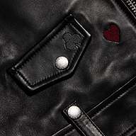 Detail of a black lambskin Blakely Embroidered Leather Jacket featuring an embroidered heart, a clover, and silver snaps.