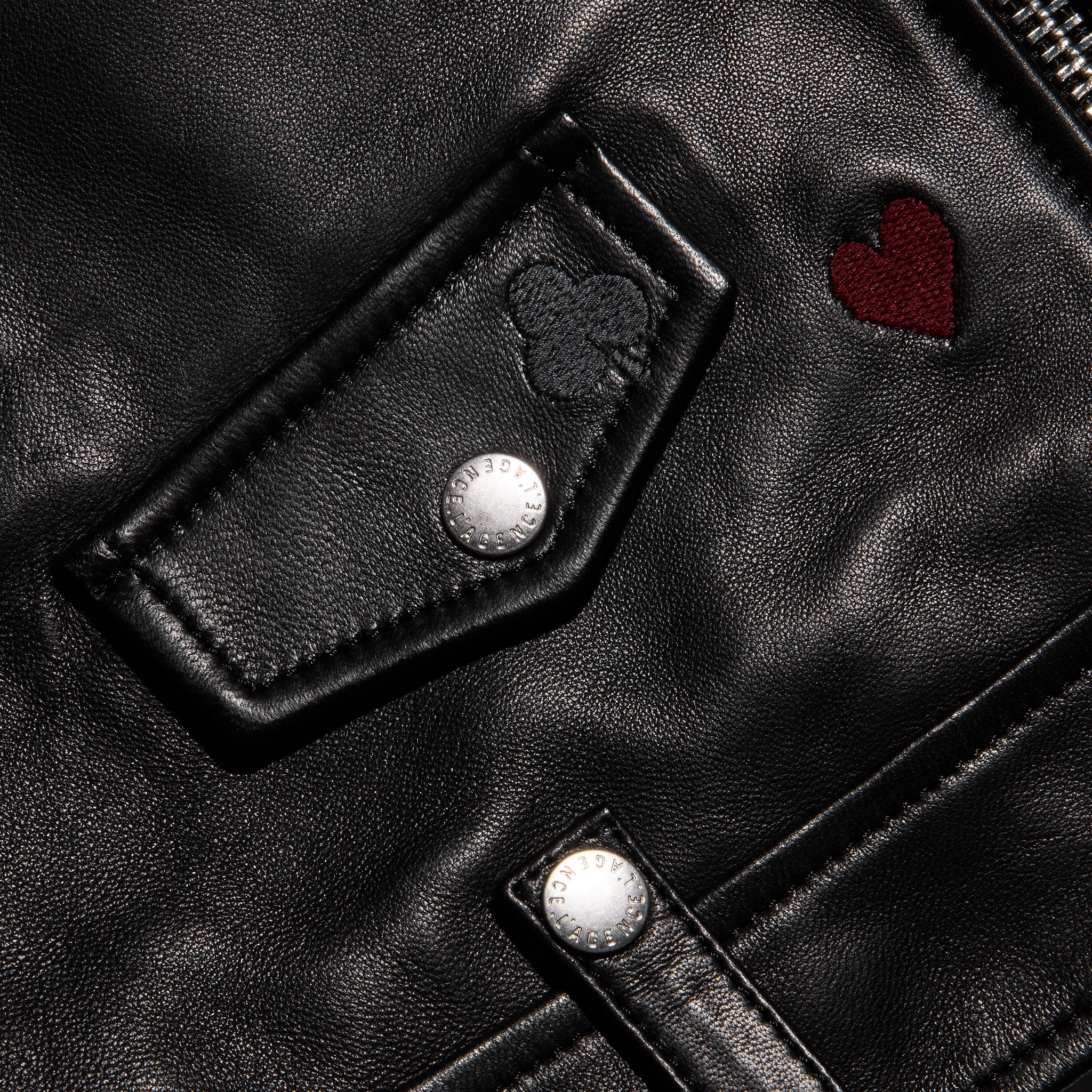 Detail of a black lambskin Blakely Embroidered Leather Jacket featuring an embroidered heart, a clover, and silver snaps.