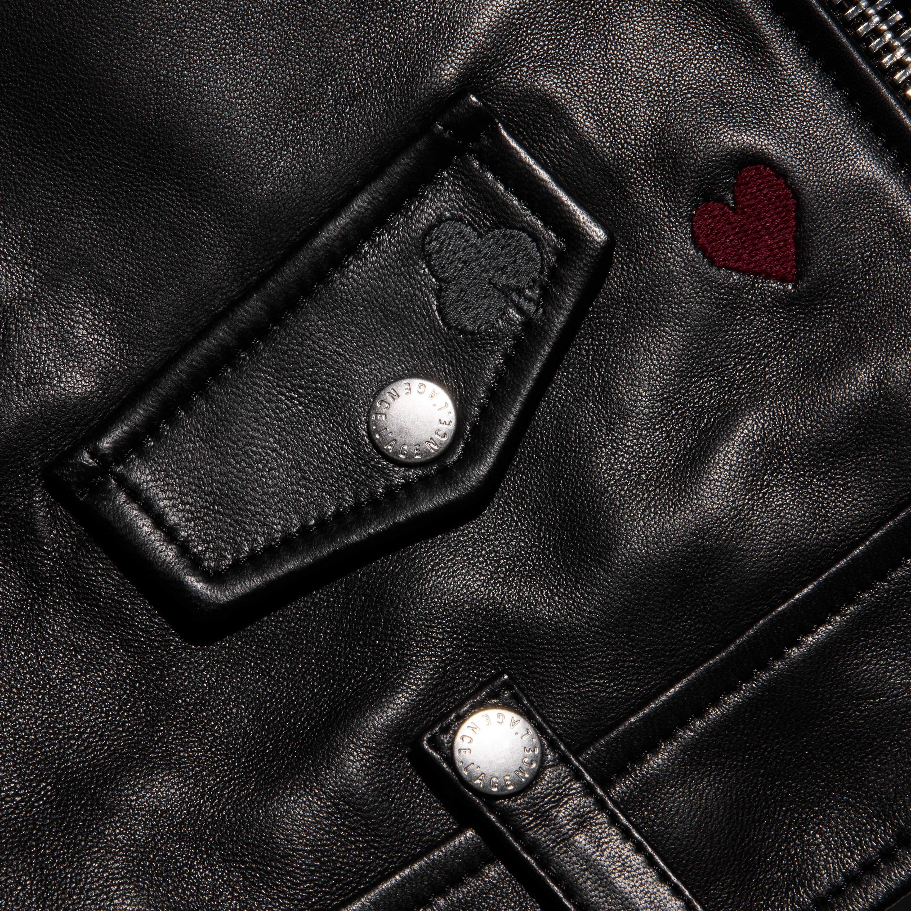 Detail of a black lambskin Blakely Embroidered Leather Jacket featuring an embroidered heart, a clover, and silver snaps.