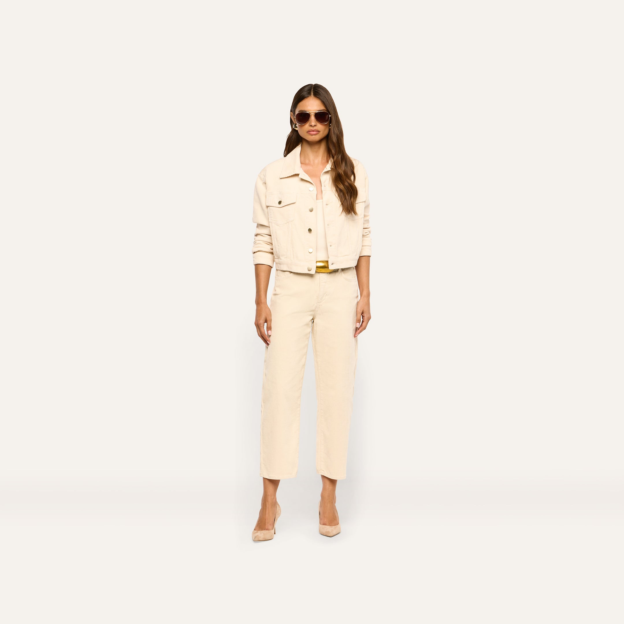 A woman wearing an Alessia Corduroy Jacket in pearl white with matching trousers and tan heels.