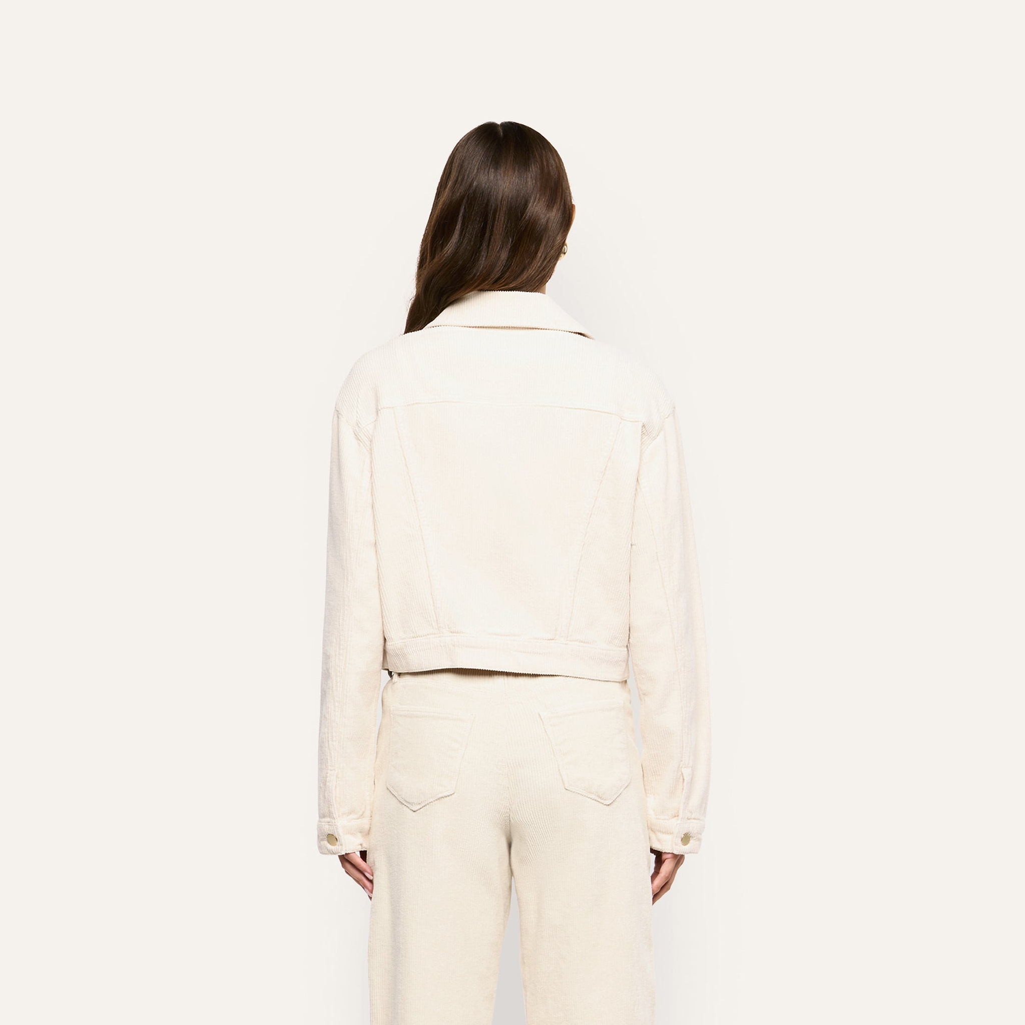 Back view of a person wearing a pearl white, cropped Alessia Corduroy Jacket and matching trousers.