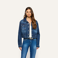 The Alessia Jean Jacket is a cropped, dark-wash denim jacket with a button-front closure and two chest pockets, worn over a white top and blue jeans.