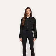 A person wearing a black cropped Alessia Jean Jacket over a white shirt and black leggings.