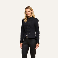 A woman stands facing forward, wearing the vintage-inspired black Victory Jacket with decorative buttons and black pants, against a plain light background.