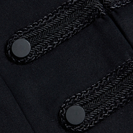 Close-up of two black, braided decorative bands with round black buttons on a dark fabric, detailing the Victory Jacket.