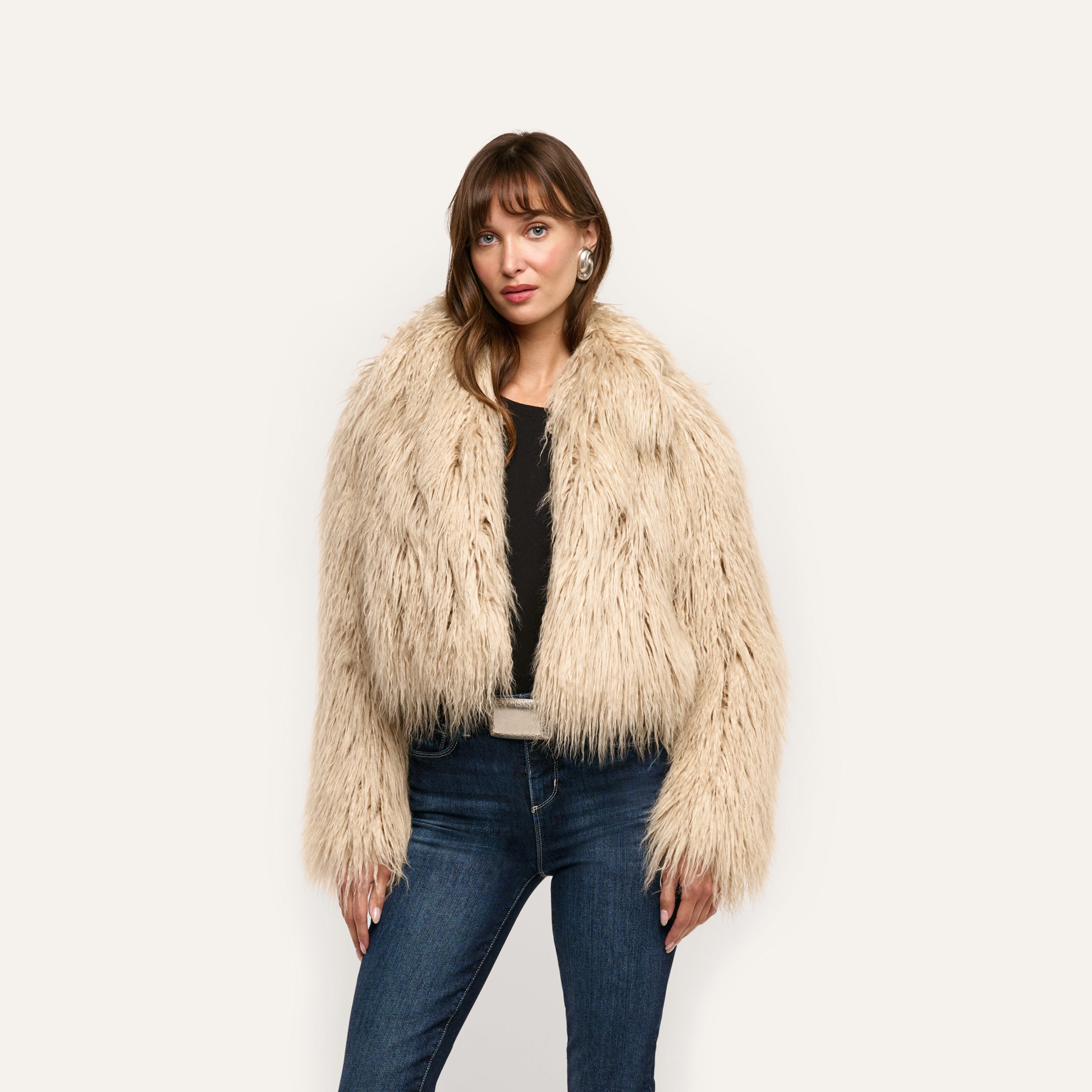 A person wearing a cropped, shag Fenella Faux Fur Coat over a black shirt and dark blue jeans.
