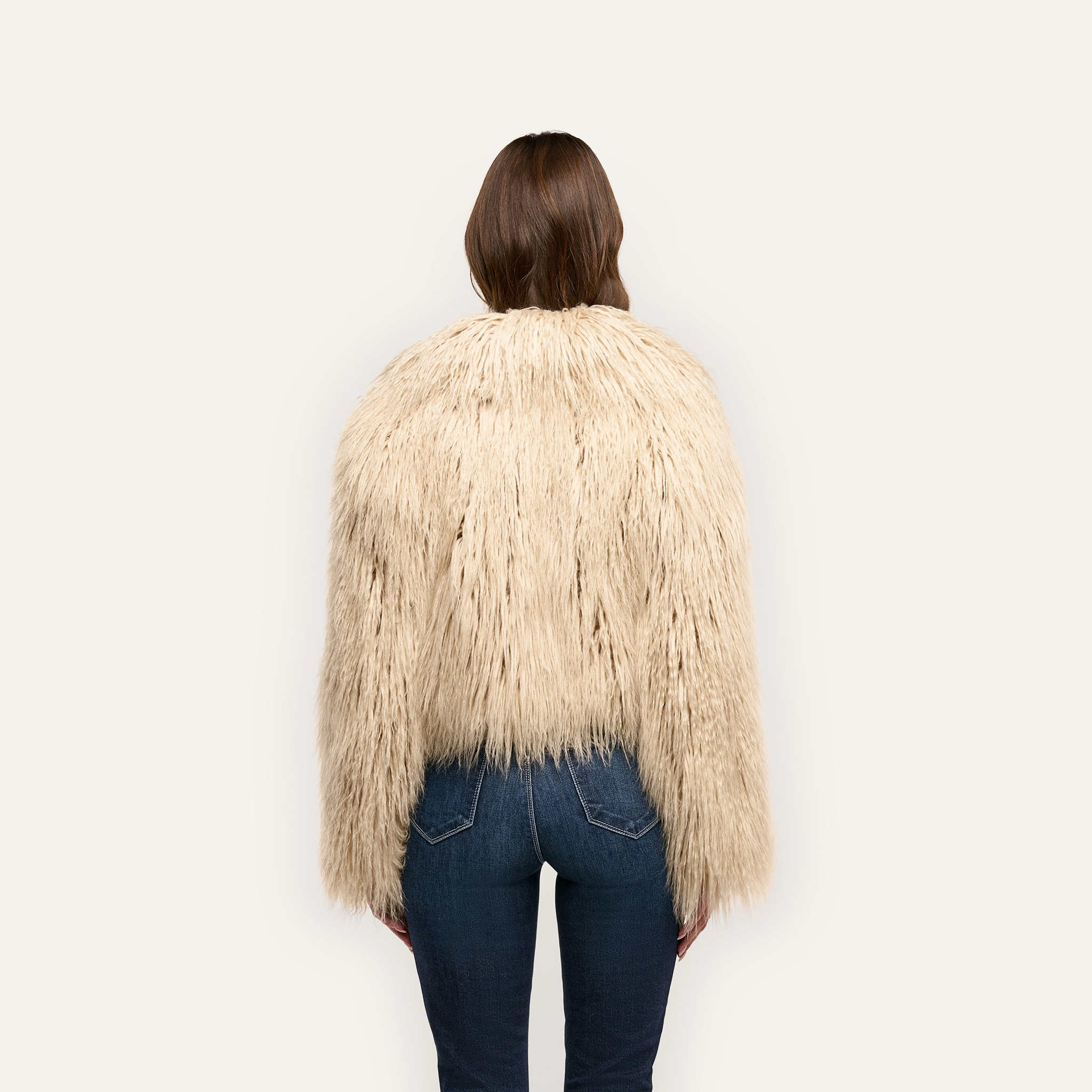 Back view of a person wearing a beige Fenella Faux Fur Coat and blue jeans.