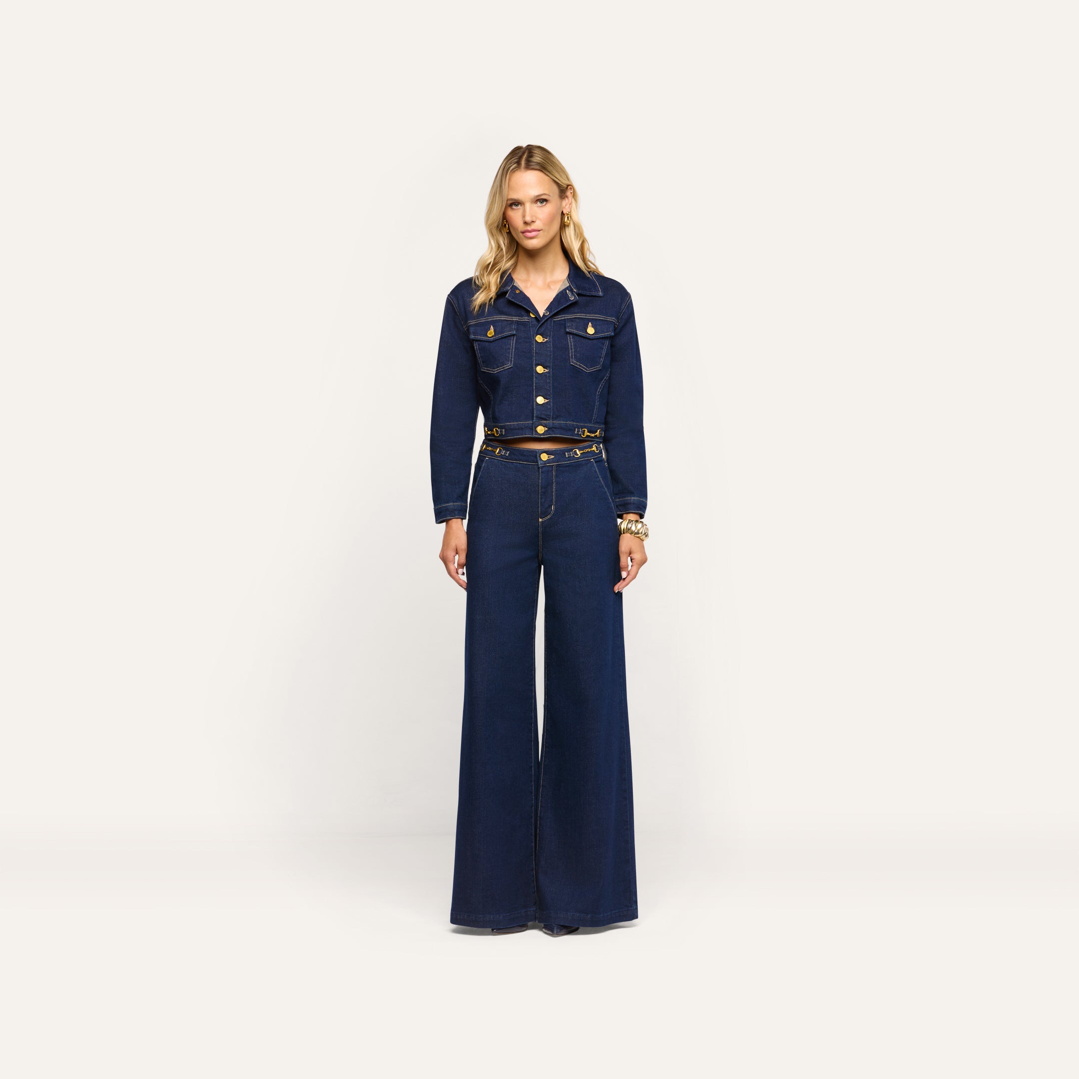 A person wearing an Edin Jean Jacket in indigo wash with gold buttons and matching wide-leg high-waisted jeans.
