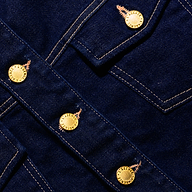 Close-up of the Edin Jean Jacket, a dark indigo wash stretch denim jacket with gold-tone metal buttons.