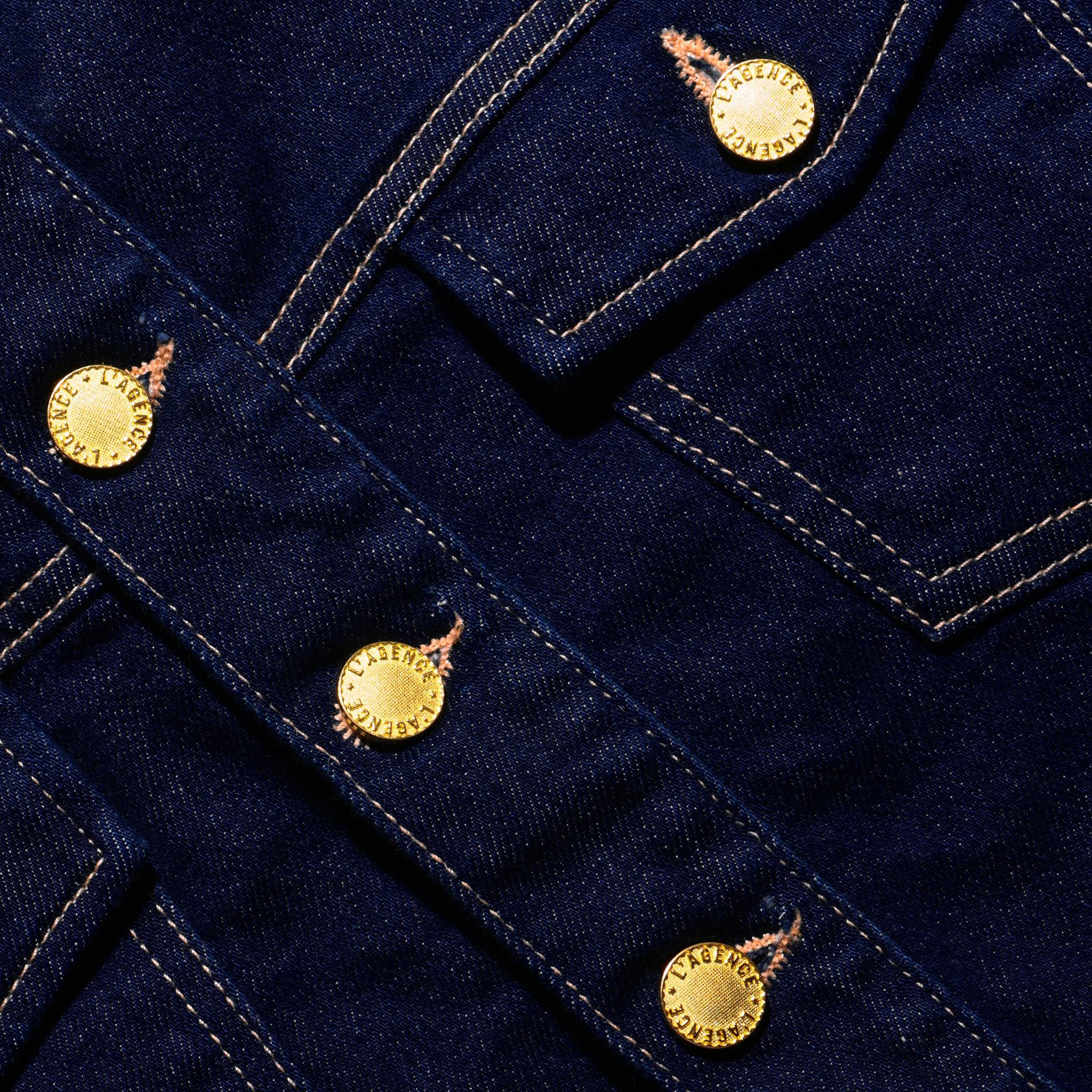Close-up of the Edin Jean Jacket, a dark indigo wash stretch denim jacket with gold-tone metal buttons.