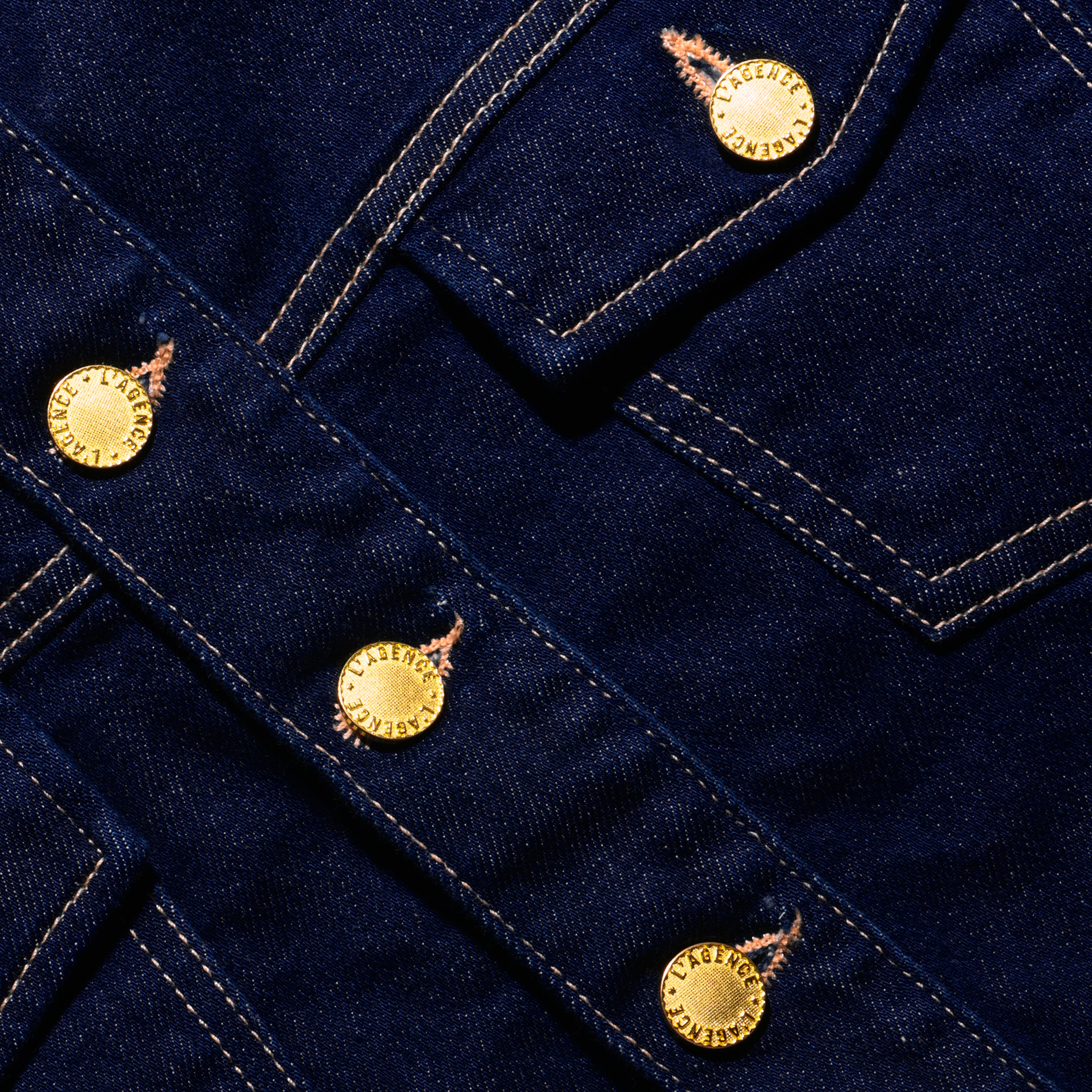 Close-up of the Edin Jean Jacket, a dark indigo wash stretch denim jacket with gold-tone metal buttons.