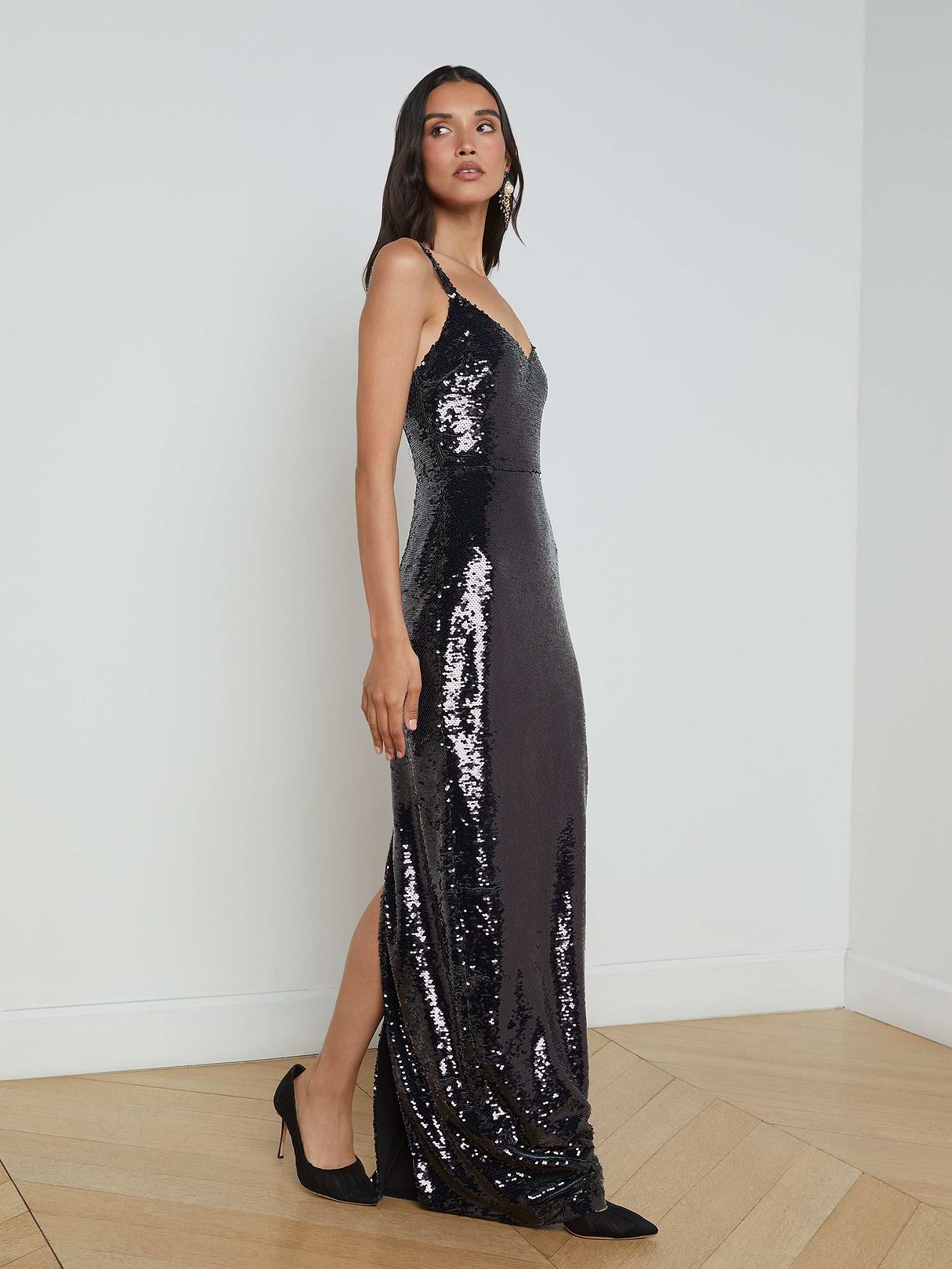 A woman wearing the Karma Sequin Maxi Dress with a structured bodice and black heels stands against a plain white background, looking slightly to her left.