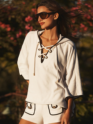 Woman wearing a white outfit with black accents in a natural setting