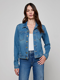 A woman wearing the Celine Jean Jacket by L’AGENCE in featherweight denim over a white top and blue slim fit jeans stands against a plain light background with one hand on her hip.