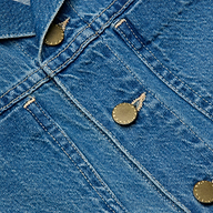 Close-up of featherweight denim fabric featuring metal buttons and visible stitching, likely part of a Celine Jean Jacket.