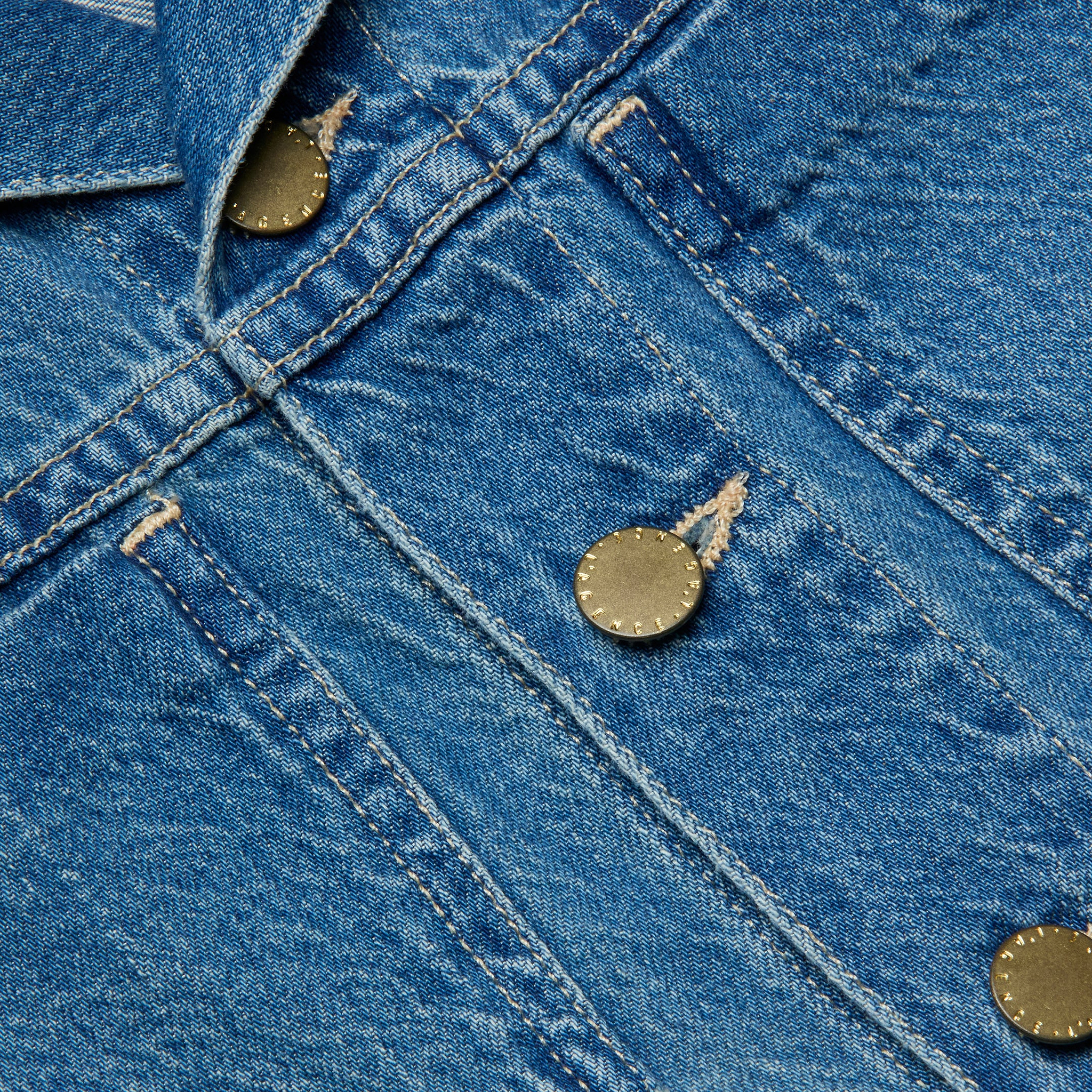 Close-up of featherweight denim fabric featuring metal buttons and visible stitching, likely part of a Celine Jean Jacket.