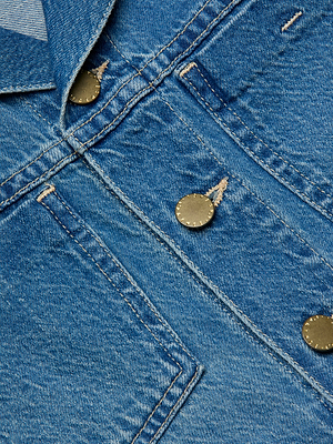 Close-up of blue featherweight denim fabric on the Celine Jean Jacket, highlighting a buttoned pocket flap, metal snap buttons, and visible stitching details.