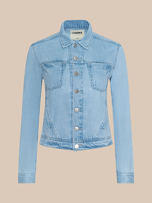 The Celine Jean Jacket features light wash denim, silver buttons, two chest pockets, and a classic collar in a slim fit. Displayed on a plain beige background with the LAGENCE label visible inside the collar.