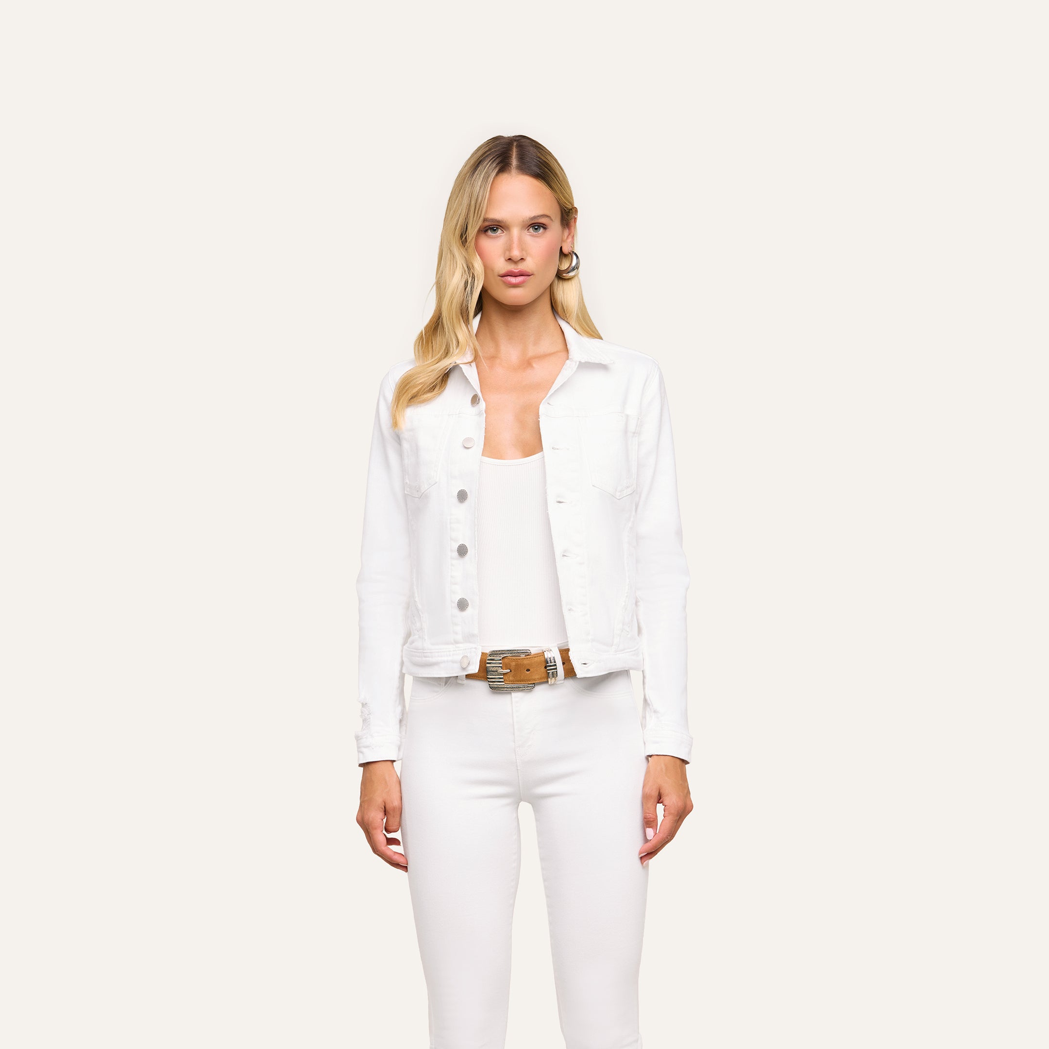A woman with long blonde hair wears the Celine Jean Jacket in optic white, paired with a white top and pants, standing against a light background with a neutral expression.