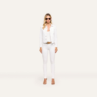 A woman with long blonde hair wears sunglasses, the Celine Jean Jacket in optic white with a relaxed fit, white pants, and tan heels, standing against a plain light background.