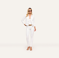 A woman stands against a plain background wearing the Celine Jean Jacket in optic white, a white top, relaxed fit white pants, a brown belt, and tan heeled sandals.