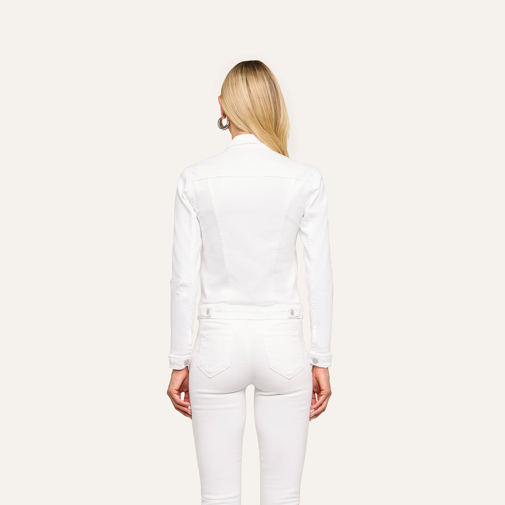 A person with long blonde hair is shown from the back, wearing the Celine Jean Jacket in optic white with matching white pants against a plain, light background.