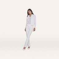 A woman stands facing forward, wearing the Celine Jean Jacket in optic white with a relaxed fit, paired with white pants, a light top, and white shoes against a plain white background.