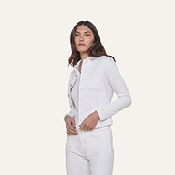 A woman with long brown hair wears the Celine Jean Jacket in optic white, featuring a relaxed fit, layered over a light top and matching white jeans, standing against a plain off-white background.