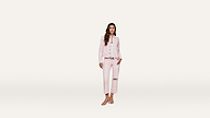 Woman wearing a light pink jacket and matching cropped pants with a knee rip, white shirt, and sandals, standing against a simple white background.