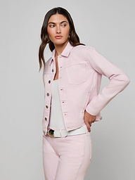 A woman wearing the slim fit Celine Jean Jacket in pastel lilac with matching jeans over a white top, standing against a plain off-white background and looking to the side with one hand on her hip.