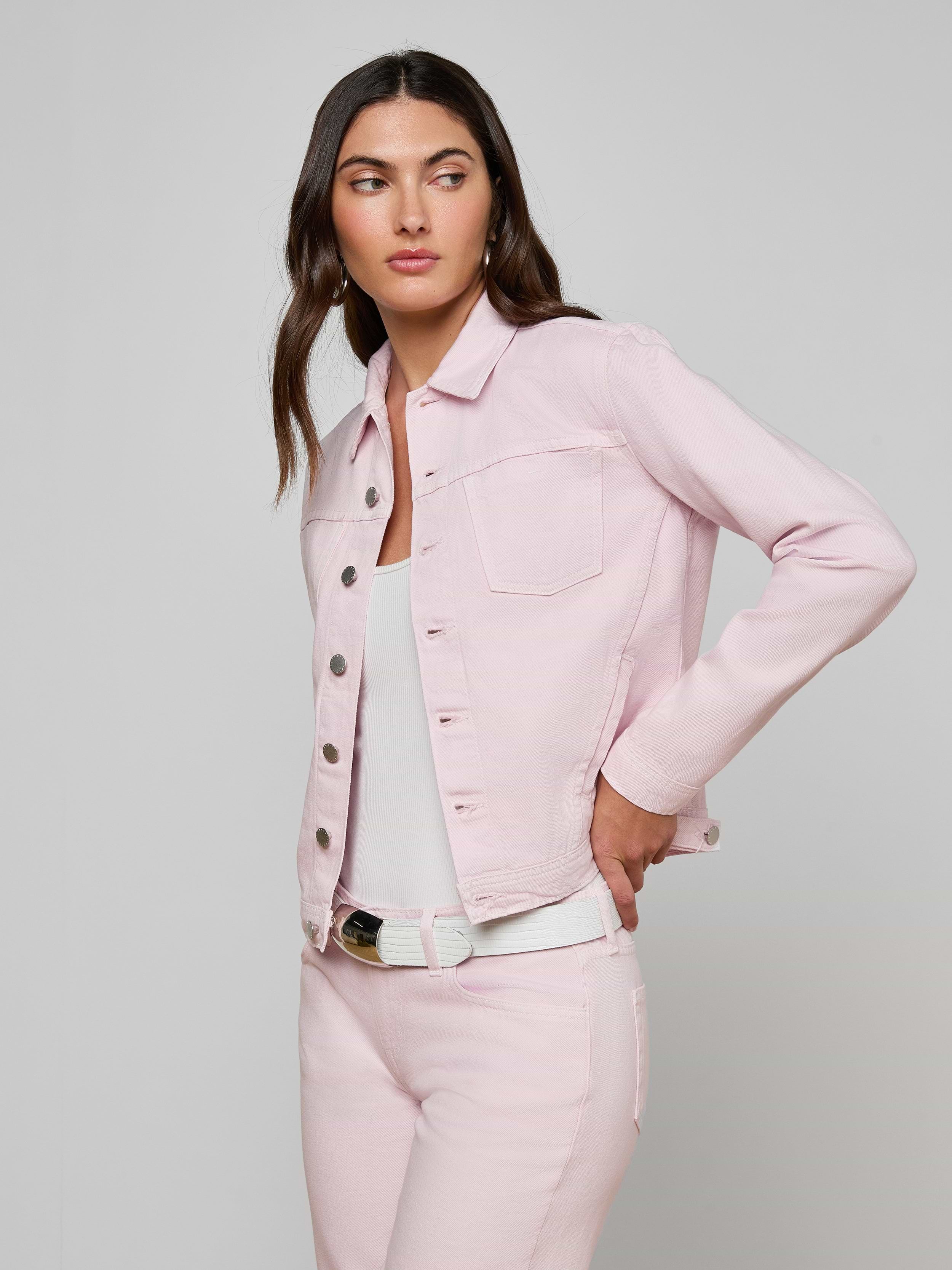 A woman wearing the slim fit Celine Jean Jacket in pastel lilac with matching jeans over a white top, standing against a plain off-white background and looking to the side with one hand on her hip.