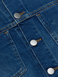 Close-up of blue denim fabric featuring yellow stitching and silver metal buttons, likely from a vintage wash Celine Jean Jacket.