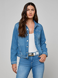 Wearing a versatile essential, a woman stands with one hand in her pocket against a plain light background—a Celine Jean Jacket by L’AGENCE layered over a white top and blue jeans creates a coordinated look.