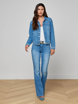 Woman wearing a blue denim jacket and jeans on a plain background