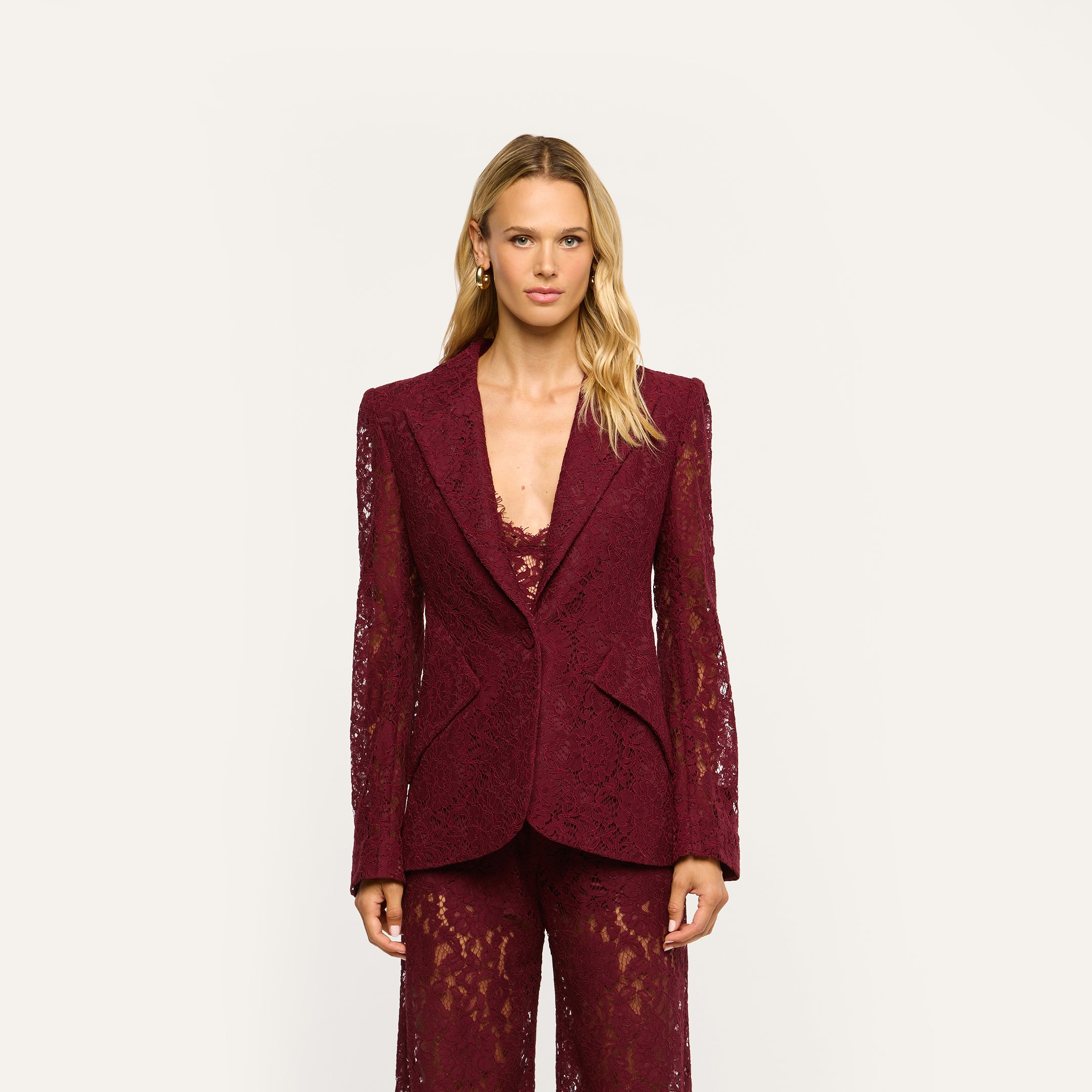 A woman wearing a deep port red Chamberlain Lace Blazer over a matching lace top and pants in a classic design.