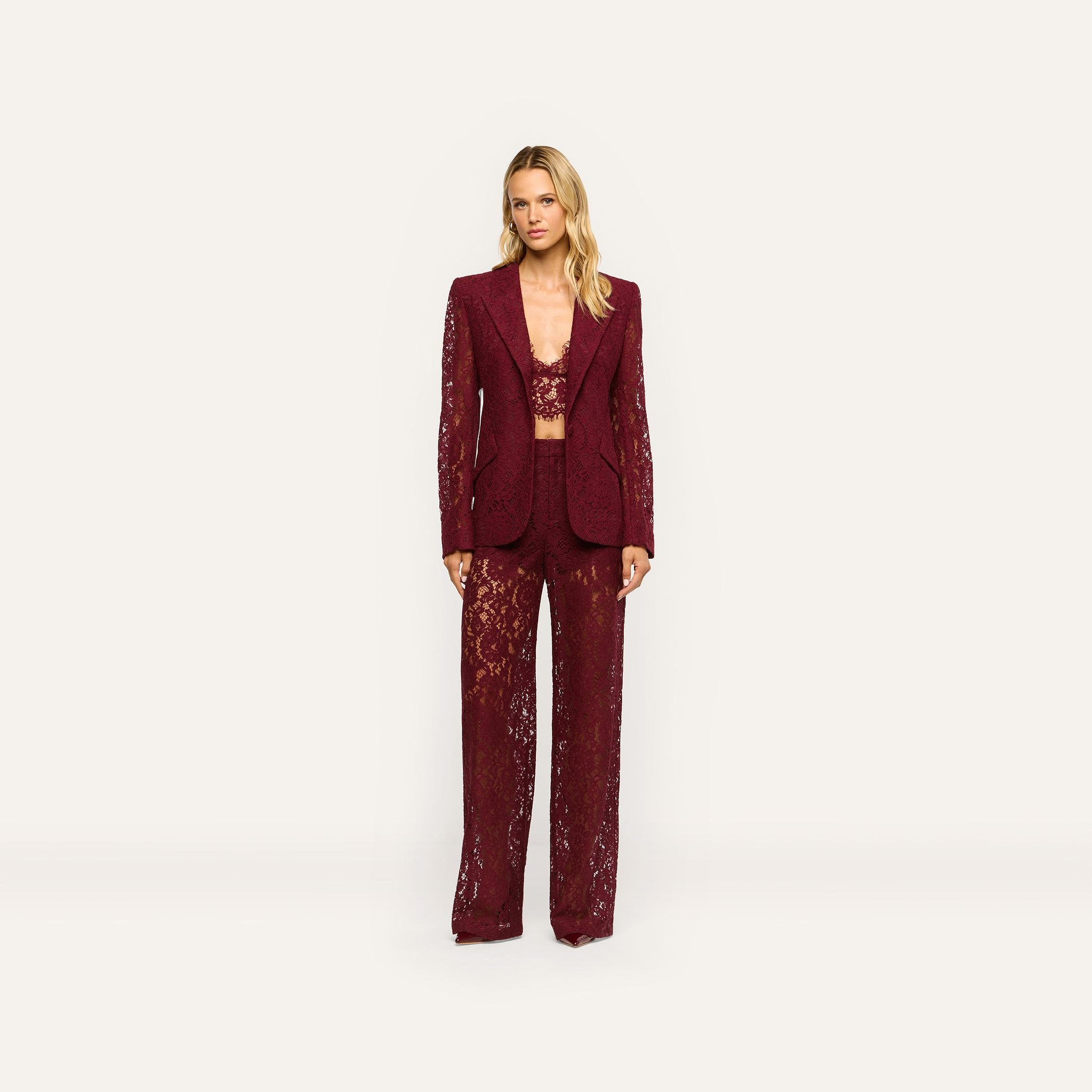 A model wears a matching deep port red Chamberlain Lace Blazer, crop top, and wide-leg trousers in a classic design.