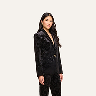 A woman with long dark hair wears the Chamberlain Velvet Blazer with matching pants, standing against a plain light background and looking confidently at the camera.