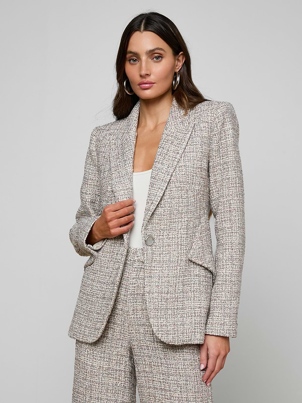 A woman wearing the Chamberlain Tweed Blazer and matching pants stands against a plain background, looking at the camera with a neutral expression.