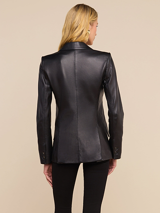 A woman with long blonde hair is shown from the back, wearing the Chamberlain Leather Blazer and black pants against a beige background.