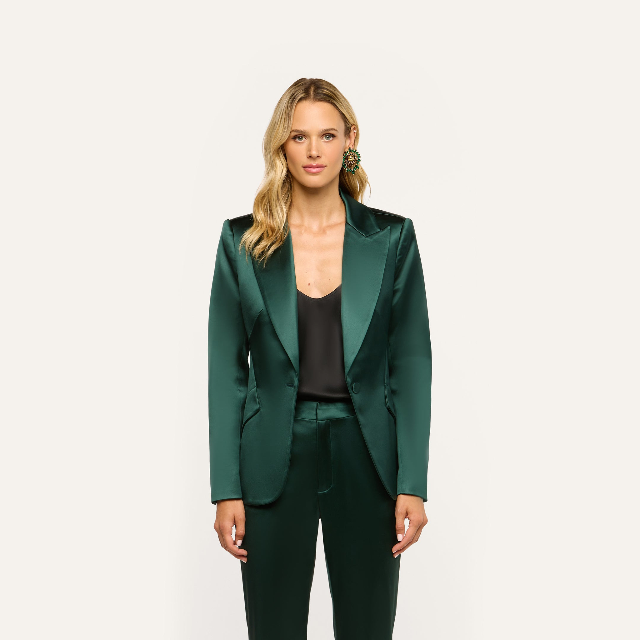 A person wearing a forest green Chamberlain Satin Blazer over a black top and matching trousers.