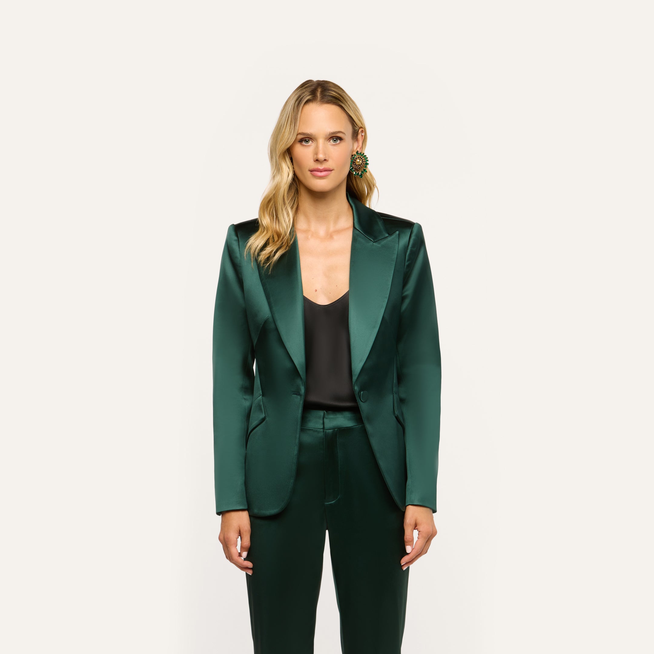 A person wearing a forest green Chamberlain Satin Blazer over a black top and matching trousers.