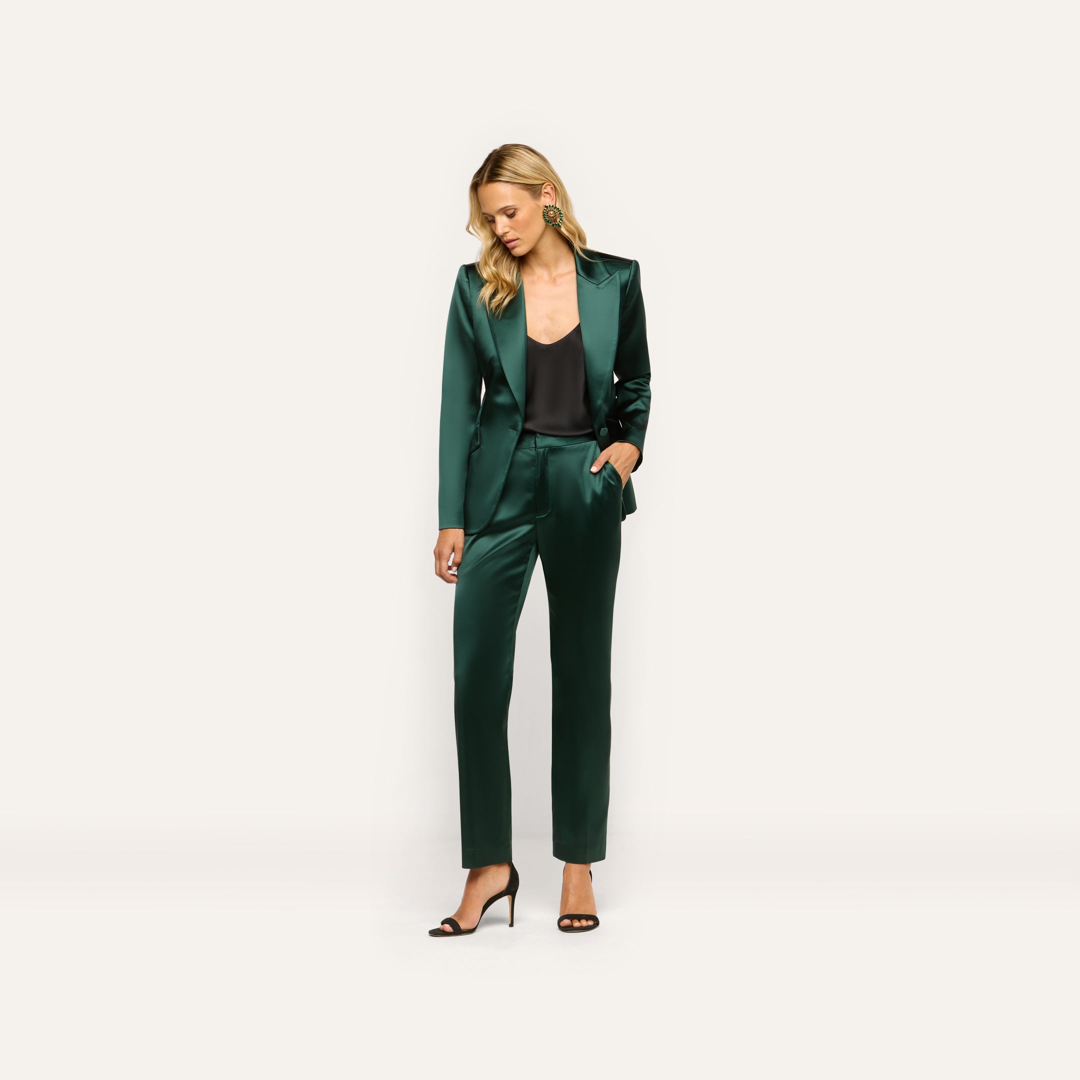 A model wears a Chamberlain Satin Blazer in forest green with matching trousers over a black camisole, paired with black heeled sandals.