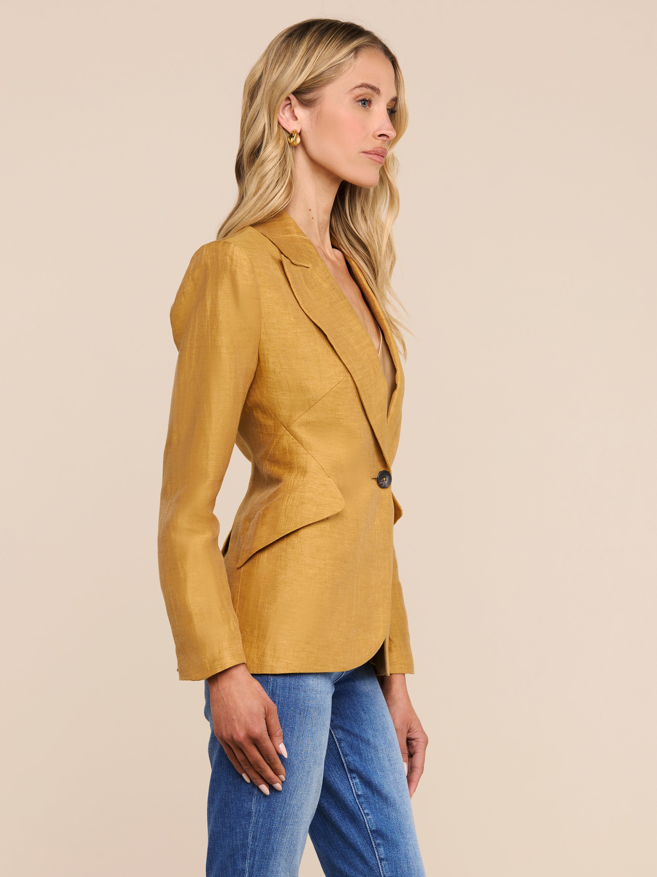 A woman with long blonde hair, wearing the Chamberlain Linen-Blend Blazer and blue jeans, stands in profile against a plain white background.