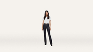 A woman stands against a plain white background, wearing a crisp white t-shirt, dark pants, black shoes, and a stylish bracelet.