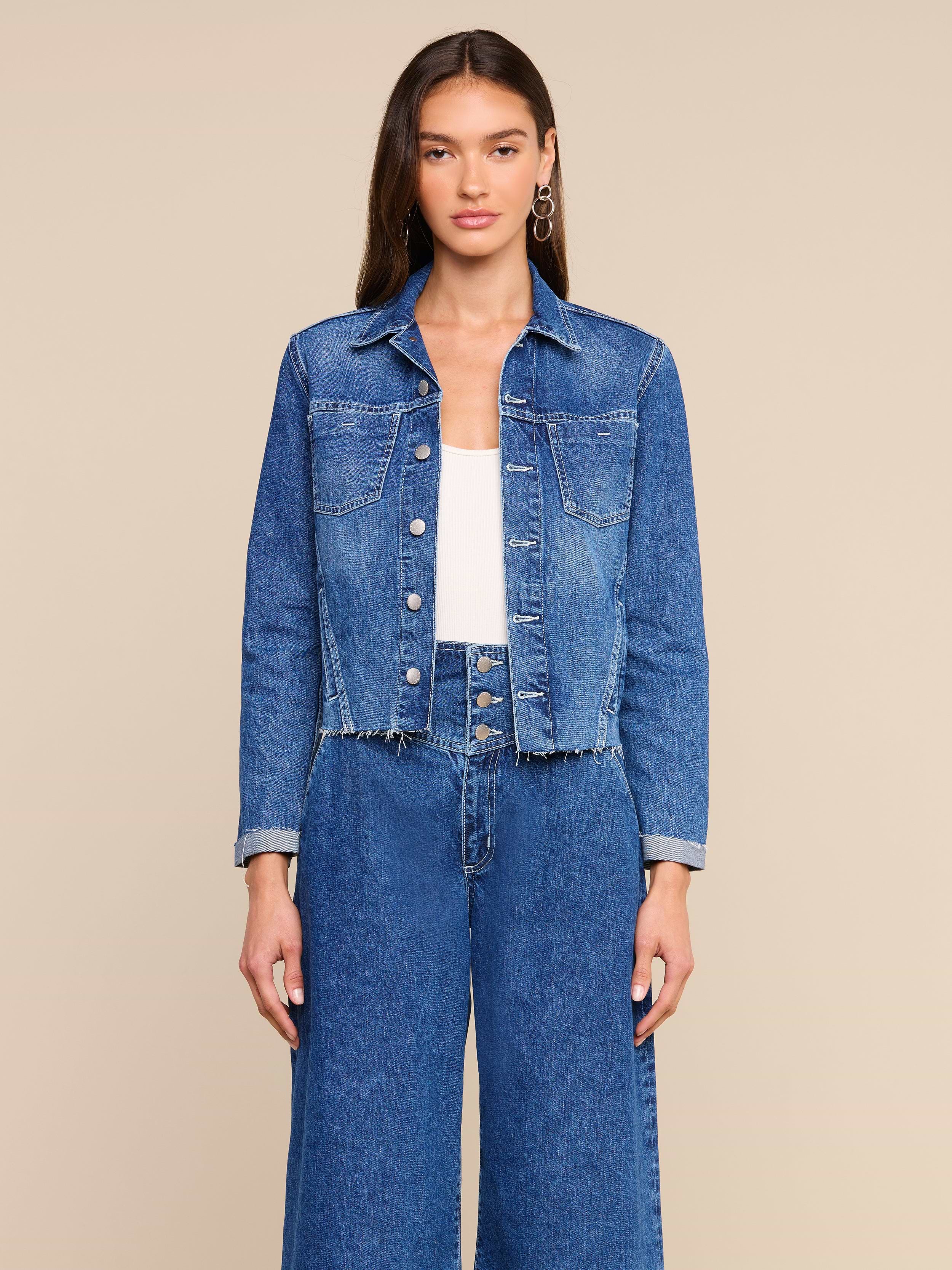 A woman wearing the Janelle Jean Jacket with a frayed hem and wide-leg jeans stands against a plain light background, facing forward with a neutral expression.