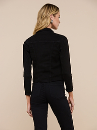 A woman with long blonde hair is shown from the back wearing the Janelle Jean Jacket and black pants, standing against a plain beige background.